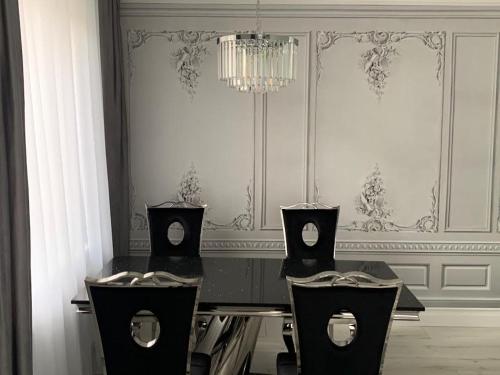 a dining room with three chairs and a chandelier at Jurata Apartament Glamour in Jurata