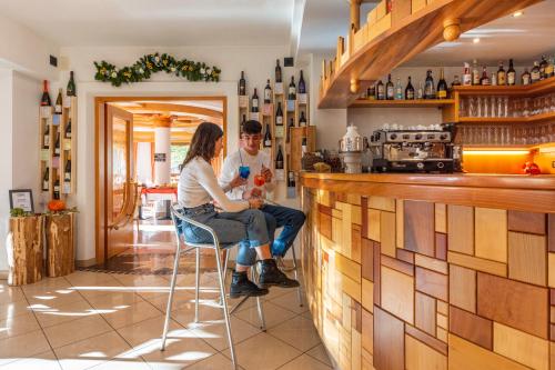a man and a woman sitting at a bar at Flos Hotel in Moena
