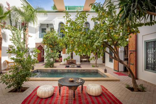 une cour avec une piscine bordée d'une table et d'arbres dans l'établissement Riad les remparts de la kasbah, à Marrakech