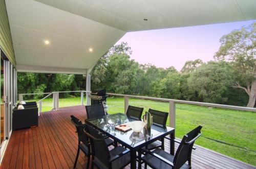 a patio with a table and chairs on a deck at Acacia Chalets Margaret River in Margaret River Town