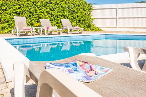 ein Tisch und Stühle neben einem Swimmingpool in der Unterkunft Villa Bermudas by Algarve Vacation in Albufeira