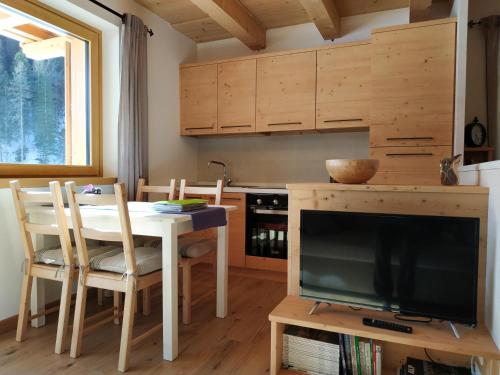 a dining room with a table and a tv and a kitchen at Tabiá sui Prá - appartamento monolocale Anna in Falcade