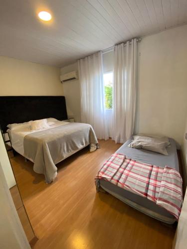 1 dormitorio con 2 camas y ventana en Casa conchas das Caravelas, en Governador Celso Ramos