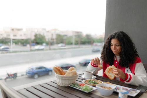 a woman sitting at a table eating a sandwich at Royal Inn Residence New Cairo in Cairo