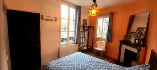a bedroom with orange walls and a bed and a fireplace at Les studios du 4 Canal - 2 grands studios indépendants proche du Loing et du centre historique de Nemours in Saint-Pierre-lès-Nemours