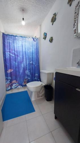 a bathroom with a toilet and a blue shower curtain at Casa Acá Diamante Gaviotas in Acapulco