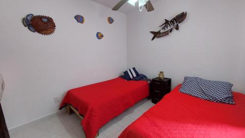 two beds in a white room with red sheets at Casa Acá Diamante Gaviotas in Acapulco