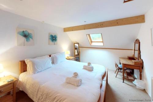 ein Schlafzimmer mit einem Bett mit zwei Handtüchern darauf in der Unterkunft BUCKLAND BREWER COB BARN 2 Bedrooms in Buckland Brewer