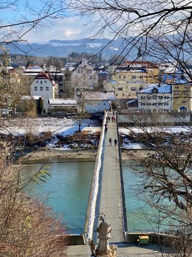 a bridge over a river with people walking on it at Ferienwohnung an der idyllischen Salzachschleife Nähe Salzburg in Laufen
