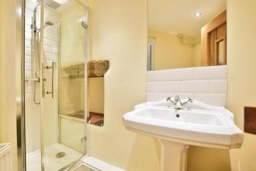 een witte badkamer met een wastafel en een douche bij Cosy retreat in Rainow, Western Peak District in Rainow