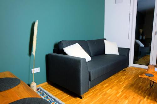 a blue living room with a black couch with white pillows at Design Apartment Nr 2 mit Terrasse und Parkplatz in Straubing