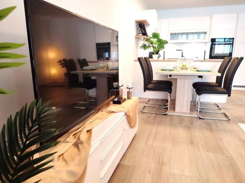 een woonkamer met een eettafel en een grote tv bij Modern Mountain Apartment - free parking & sauna in Obertauern