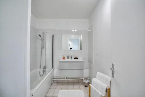 a white bathroom with a tub and a sink at Studio spacieux avec terrasse et parking in Viry-Châtillon