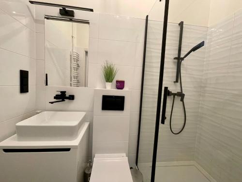 biała łazienka z umywalką i prysznicem w obiekcie Słoneczny Apartament Koszykowy! w Warszawie