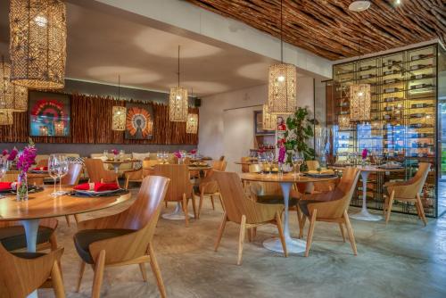 a restaurant with wooden tables and chairs and chandeliers at Villa Pantai Boutique Hotel Maragogi in Maragogi