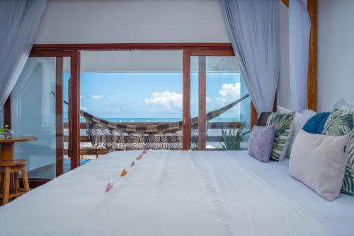 Villa Pantai Boutique Hotel Maragogi في ماراغوغي: غرفة نوم مع سرير وإطلالة على المحيط