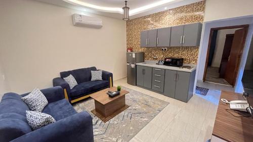 a living room with blue couches and a kitchen at فيو إن للشقق الفندقية - المحالة in Abha