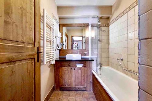 une salle de bain avec une baignoire, un lavabo et un miroir dans l'établissement Arc 1950 - Chalet des Lys - appt Luxe 4 pers, à Arc 1950