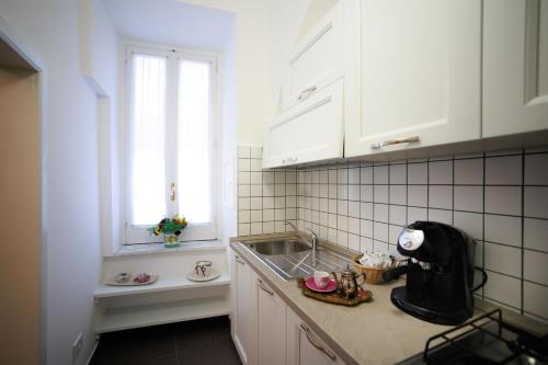 una cucina con armadi bianchi, lavandino e finestra di B&B CORSO VITTORIO a Venosa