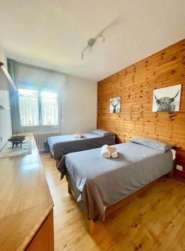 卡瓦萊塞的住宿－Tina's House - Alpine Stay Apartments，一间卧室设有两张床和木墙