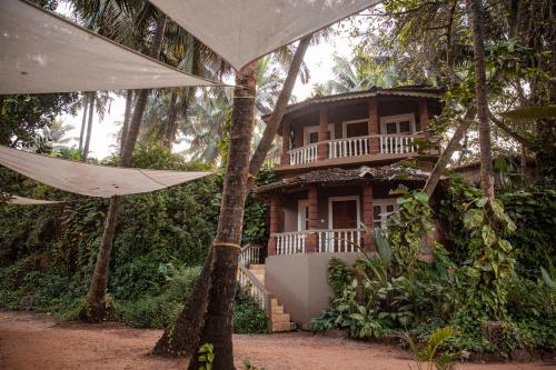 a house in the woods with a hammock in front of it at Anahata Retreat Sea Front Resort Ashvem in Mandrem