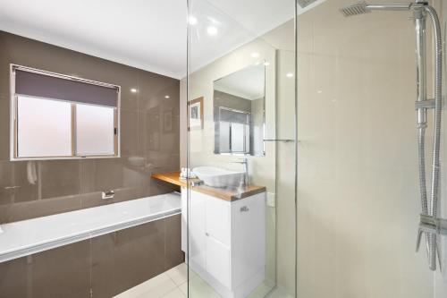 ムールーラバにあるRegency 3 Bedroom Central Town Houseのガラスのシャワーと洗面台を備えたバスルーム