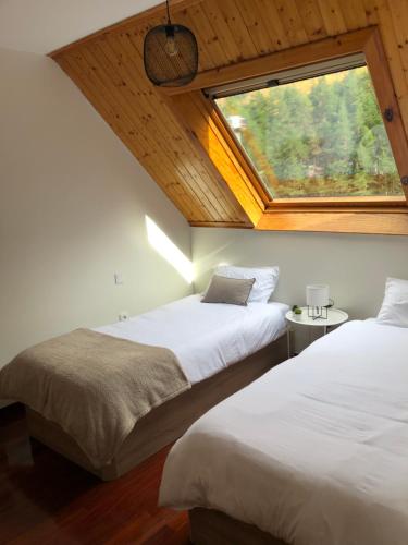 2 Betten in einem Zimmer mit Fenster in der Unterkunft Ático europa, Canfranc estación in Canfranc-Estación