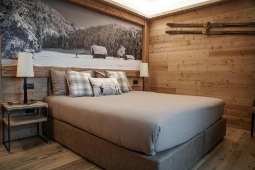 sypialnia z łóżkiem w drewnianej ścianie w obiekcie Sci Sport rooms & suites w mieście Bormio