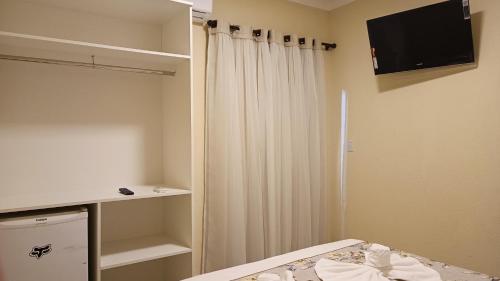 a bedroom with a bed and a tv and a closet at Belo quinto Styles pousada in Brotas