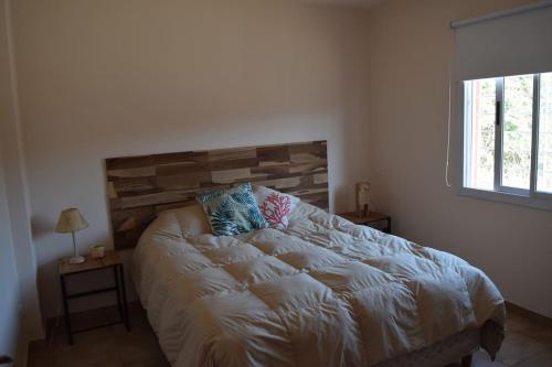 1 dormitorio con 1 cama con cabecero de madera y ventana en departamento chateau en Córdoba