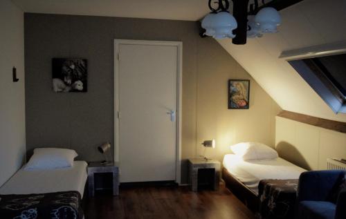 a small room with two beds and a door at Hoeve de Mertel in Biezenmortel