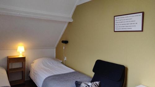 a bedroom with a bed and a chair and a sign on the wall at Hoeve de Mertel in Biezenmortel