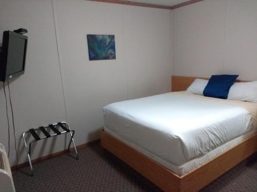 a bedroom with a bed and a flat screen tv at Sundown Motel in Watrous