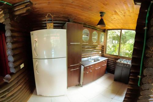 a kitchen with a refrigerator in a log cabin at Eco Cabañas San Lorenzo in La Mesa