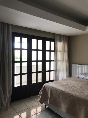 a bedroom with a bed and two large windows at Pousada Cantinho do Sossego in Petrolina