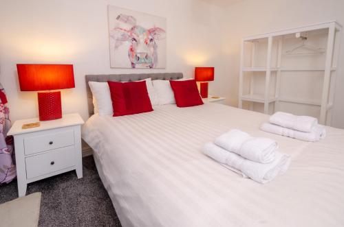 a bedroom with a large white bed with red pillows at Squirrels in Elterwater