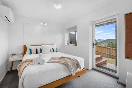 Habitación blanca con cama y balcón. en Cosy Cottesloe - 2 Bedroom Unit - Free Parking - Free WIFI en Lindisfarne