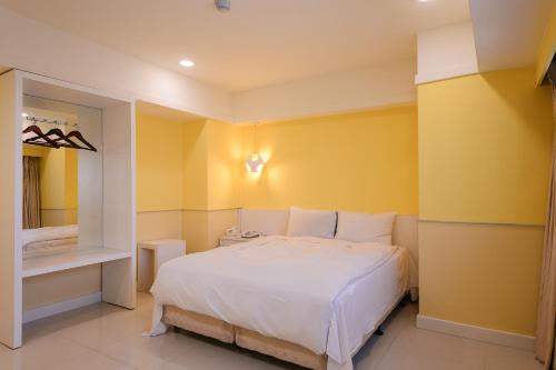 a bedroom with a white bed and yellow walls at KIWI-Taichung Station Branch 1 in Taichung