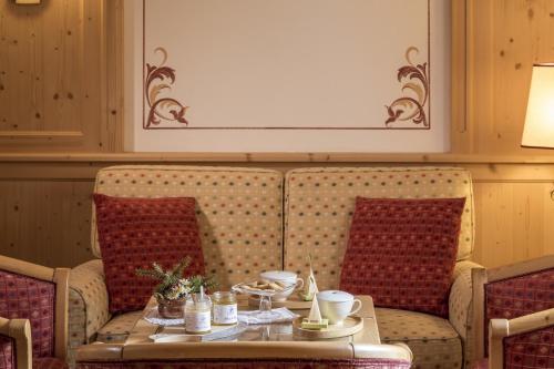 a room with a table and a couch with a coffee table at Hotel Chalet Del Sogno in Madonna di Campiglio