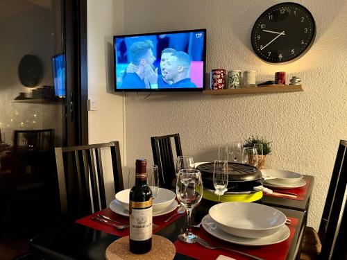 een eettafel met een fles wijn en een klok bij Le Val d'Huez, Vue sur le Village et le Domaine in Huez