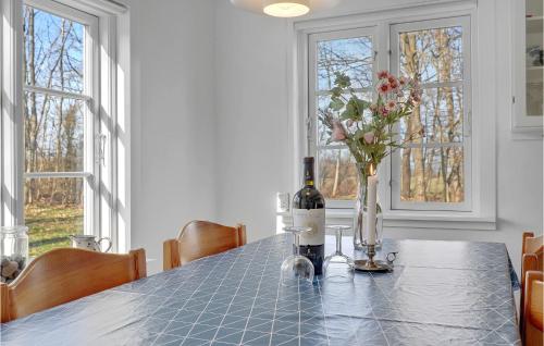 a dining room table with a bottle of wine and flowers at Fodermesterhuset in Gudhjem