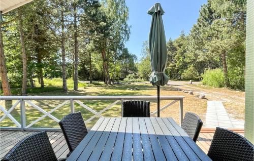 a wooden table with a closed umbrella on a deck at Cozy Home In Aakirkeby With Wifi in Vester Sømarken