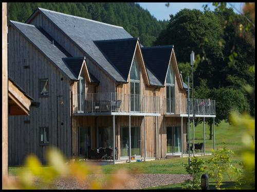 a large wooden building with a balcony and a house at Mains of Taymouth Country Estate 5* Gallops Apartments in Kenmore