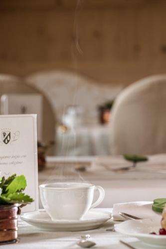 a table with two cups and plates on it at Hotel Chalet Del Sogno in Madonna di Campiglio