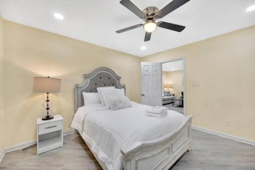 Cozy 2 Bedroom Pineville-Matthews Duplex Sleeps 8 في تشارلوت: غرفة نوم بسرير أبيض مع مروحة سقف