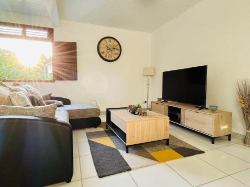 ein Wohnzimmer mit einem Sofa und einem TV in der Unterkunft Appartement Manou in Le Lamentin