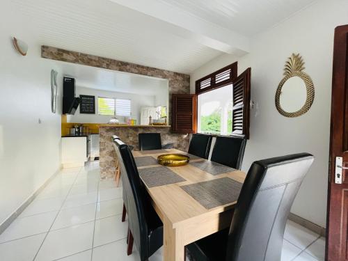 comedor con mesa de madera y sillas negras en Appartement Manou en Le Lamentin