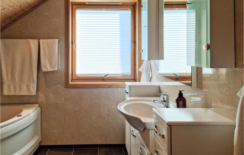 een witte badkamer met een wastafel en een spiegel bij Awesome Home In Risr With House Sea View in Risør