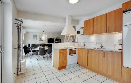 a kitchen with wooden cabinets and a dining room at Amazing Home In Hvide Sande With Sauna in Bjerregård