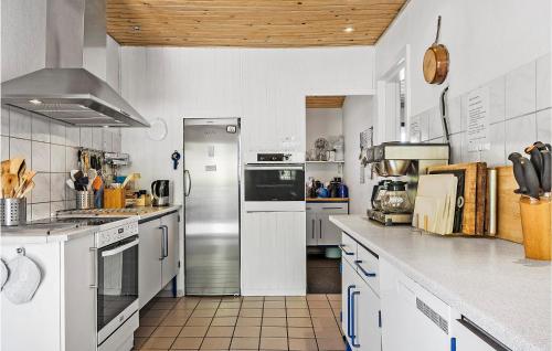 a large kitchen with white appliances and wooden ceilings at Lovely Home In Fredericia With Wifi in Fredericia